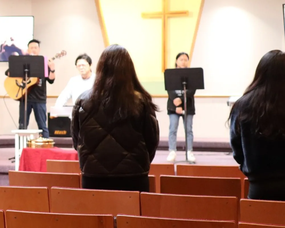 주일 연합예배에서 찬양팀과 함께 서서 찬양하는 성도들의 뒷모습